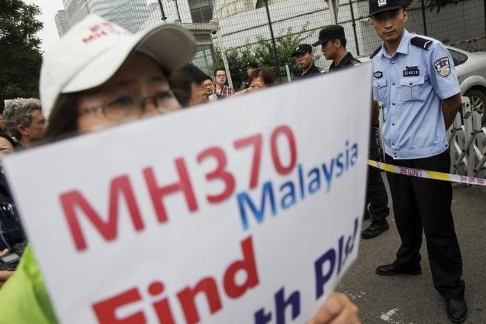 A woman whose relative was aboard Malaysia Airlines flight MH370 holds placard after police stopped protesting relatives from entering a road leading to the Malaysian embassy in Beijing August 7, 2015. REUTERS/Damir Sagolj