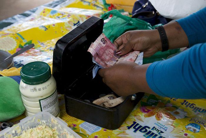 An informal trader counts out change in her cash box at her stall in Hillcrest, west of Durban, South Africa, January 11, 2016. REUTERS/Rogan Ward