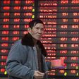 An investor walks past an electronic screen showing stock information at a brokerage house in Nanjing, Jiangsu province, China January 14, 2016. REUTERS/China Daily