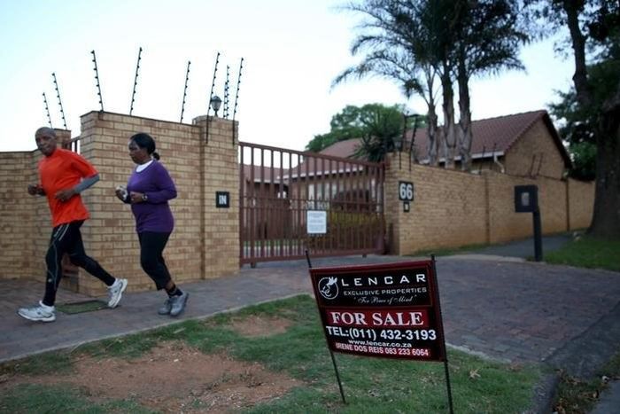A couple jogs past a "for sale" sign outside a house in Johannesburg, February 1, 2016. REUTERS/Siphiwe Sibeko