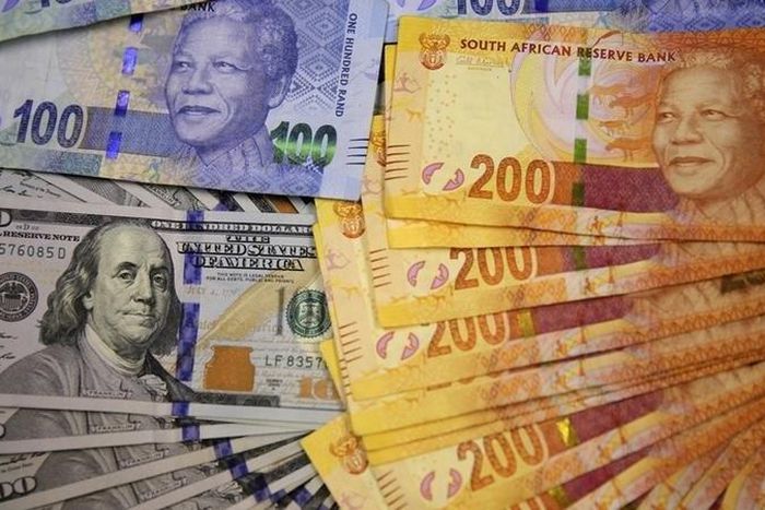 South African bank notes featuring images of former South African President Nelson Mandela (R) are displayed next to the American dollar notes in this photo illustration in Johannesburg, in a file photo. REUTERS/Siphiwe Sibeko