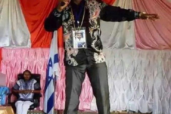 Pastor Sidney standing on his members during sermon