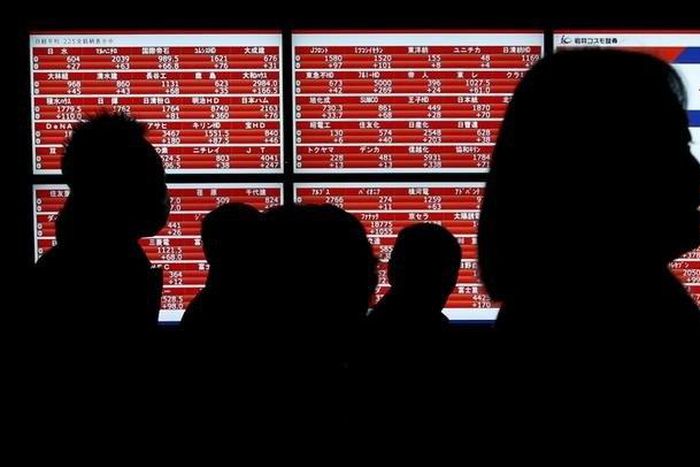 Pedestrians walk past an electronic stock quotation board outside a brokerage in Tokyo, Japan January 22, 2016. REUTERS/Toru Hanai