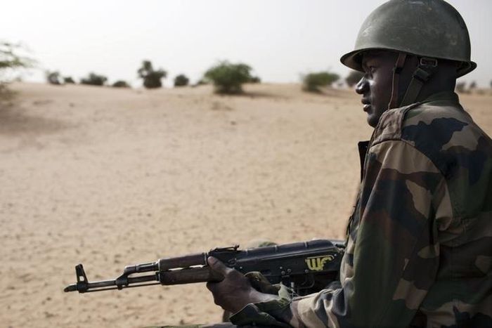 A Malian soldier, holding an AK-47 rifle, rides in a pick-up truck during a military escort outside Timbuktu, Mali, July 27, 2013.   REUTERS/Joe Penney