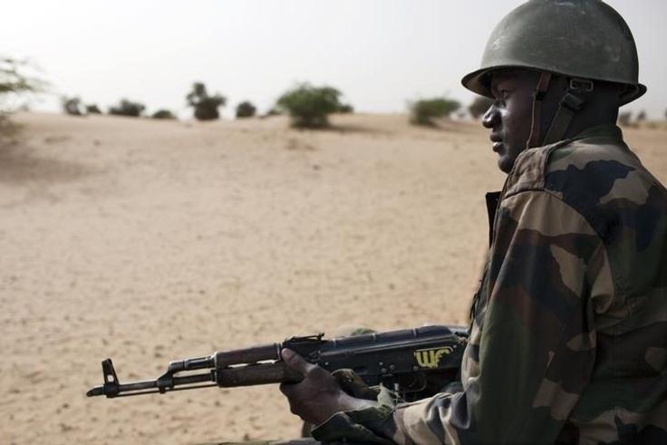 A Malian soldier, holding an AK-47 rifle, rides in a pick-up truck during a military escort outside Timbuktu, Mali, July 27, 2013. REUTERS/Joe Penney