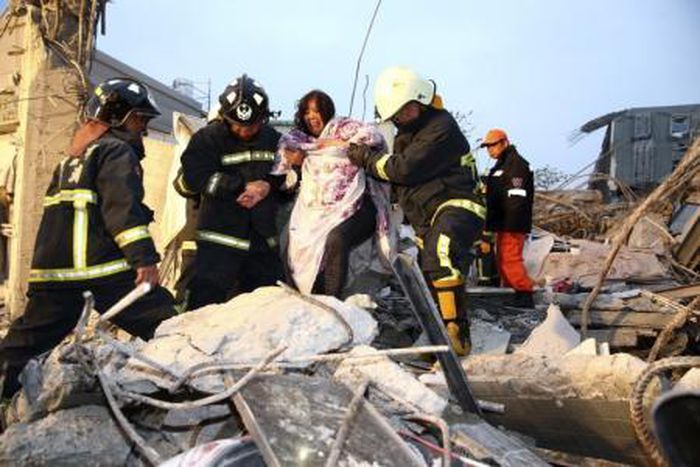 Rescue personnel help a victim at a damaged building after an earthquake in Tainan, southern Taiwan, February 6, 2016.