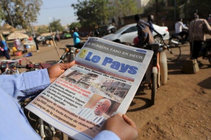 A man reads newspaper headlines that talk about the al Qaeda attack on the Splendid Hotel and Cappuccino that killed at least 28 people from at least seven countries in Ouagadougou, Burkina Faso, January 18, 2016. REUTERS/Joe Penney