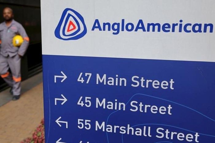 A worker walks past a board outside Anglo American offices in Johannesburg, August 21, 2015. REUTERS/Siphiwe Sibeko