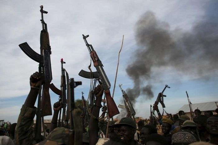Rebel fighters hold up their rifles as they walk in front of a bushfire in a rebel-controlled territory in Upper Nile State, South Sudan February 13, 2014.    REUTERS/Goran Tomasevic