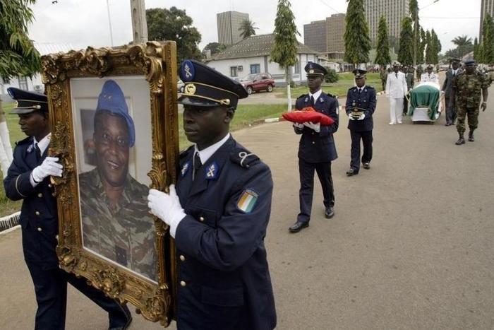 Ivory Coast soldiers carry the portrait and coffin of Robert Guei, former president and army general, during a funeral procession held at the Ivorian Army Chief of Staff headquarters in Abidjan in a file photo. REUTERS/Thierry Gouegnon