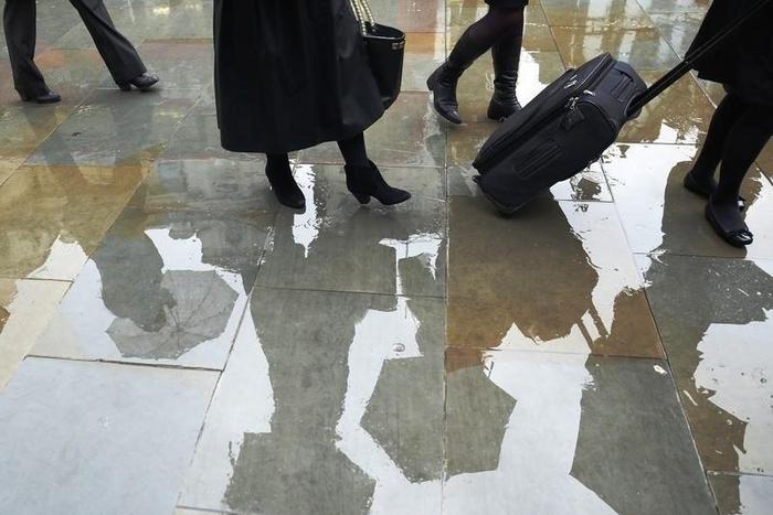People queue to enter the court building during a heavy rain storm outside the High Court in London November 14, 2014. REUTERS/Luke MacGregor