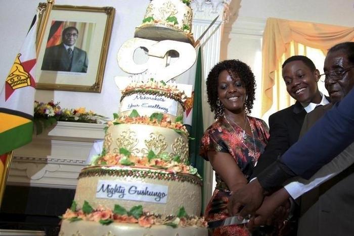 Zimbabwean President Robert Mugabe (R) is helped by his wife Grace (L) and son Chatunga (C) to cut a cake to celebrate his 92nd birthday at State House in Harare, February 22, 2016. Mugabe turned 92 on Sunday. REUTERS/Philimon Bulawayo