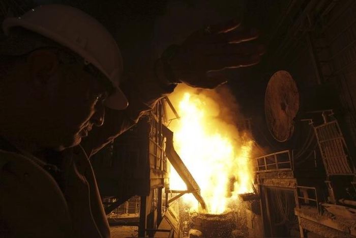 An engineer covers his face as workers pour molten iron into a container at a factory belonging to Ezz Steel, Egypt's largest steel producer, at an industrial complex in Sadat City, 94 km (58 miles) north of Cairo, April 17, 2013. REUTERS/Amr Abdallah ...