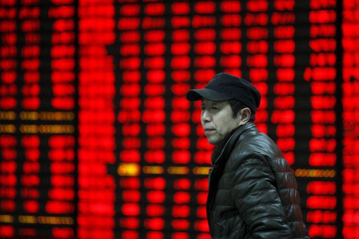 An investor walks past an electronic board showing stock information at a brokerage house in Huaibei, Anhui province, January 29, 2016 REUTERS/China Daily