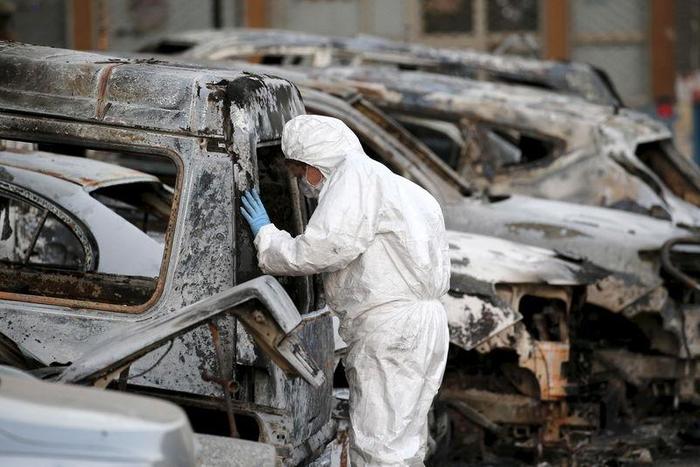 A French police officer inspects burned vehicles outside the Splendid Hotel in Ouagadougou, Burkina Faso, January 17, 2016. REUTERS/Joe Penney