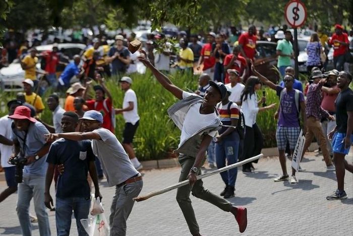 Students throw stones during a confrontation with security guards as they protest over planned increases in tuition fees outside the (UJ) University of Johannesburg October 22, 2015. REUTERS/Siphiwe Sibeko