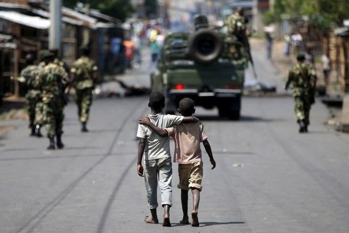 Boys walk behind patrolling soldiers in Bujumbura, Burundi, May 15, 2015 REUTERS/Goran Tomasevic