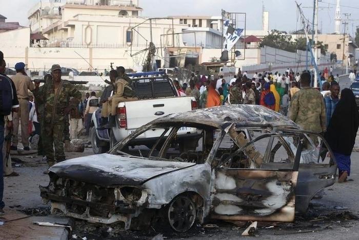 A car suspected by the Somali police to have been used in a bomb attack is seen as residents gather to view the damage at the scene of the attack near Somali Youth League Hotel, known as SYL hotel, in Hamarweyne district in Mogadishu, February 27, 2016...