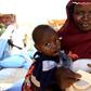 An internally displaced woman carries her child as she waits to receive food relief at a distribution center provided by the World Food Program at the Aboushouk camp in Al Fasher, North Darfur, Sudan, November 17, 2015. REUTERS/Mohamed Nureldin Abdalla...