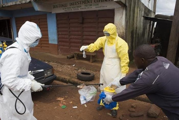 Health workers in protective equipment handle a sample taken from the body of someone who is suspected to have died from Ebola virus, near Rokupa Hospital, Freetown October 6, 2014.  REUTERS/Christopher Black/WHO/Handout via Reuters