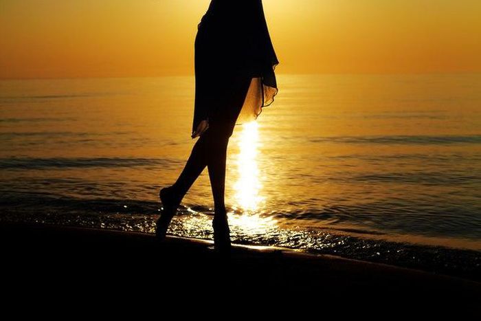 Silhouette of woman raising hands to the sky