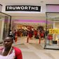 Shoppers walk past a Truworths shop with Sale advertisements on its windows at the Sandton shopping mall in Johannesburg January 30, 2012. REUTERS/Siphiwe Sibeko