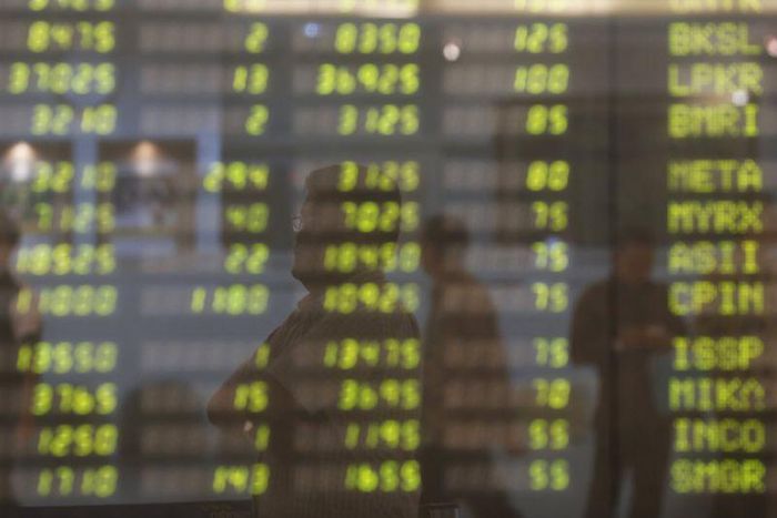 A man stands near an electronic board showing the stock market index at the Bank Mandiri Sekuritas trading floor in Jakarta November 25, 2015. REUTERS/Beawiharta