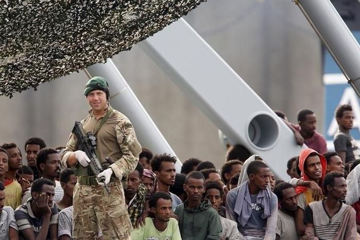 Migrants are seen aboard the British vessel HMS Enterprise before disembarking in the Sicilian harbour of Catania, Italy, October 6, 2015. REUTERS/Antonio Parrinello