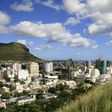 A tour guide stands with a group of tourists at a viewpoint overlooking Port Louis in a file photo. REUTERS/Ed Harris