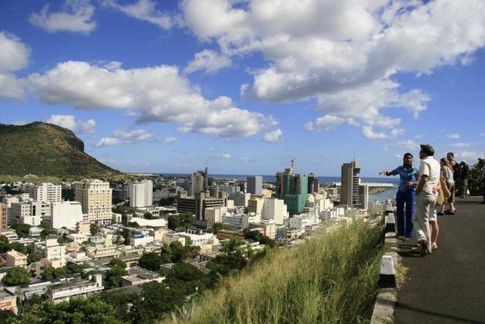 A tour guide stands with a group of tourists at a viewpoint overlooking Port Louis in a file photo. REUTERS/Ed Harris