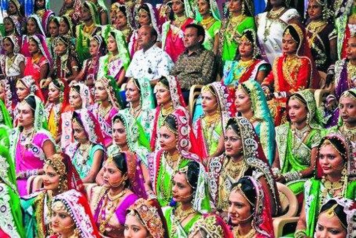 Indian diamond trader Mahesh Savani (top centre) wearing white, poses for a group photo along with brides before mass wedding hosted by him in Surat, India.