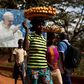 Women carrying fruits and vegetables on their heads walk past a billboard with a photograph of Pope Francis, in Bangui, Central African Republic, November 26, 2015. REUTERS/Siegfried Modola