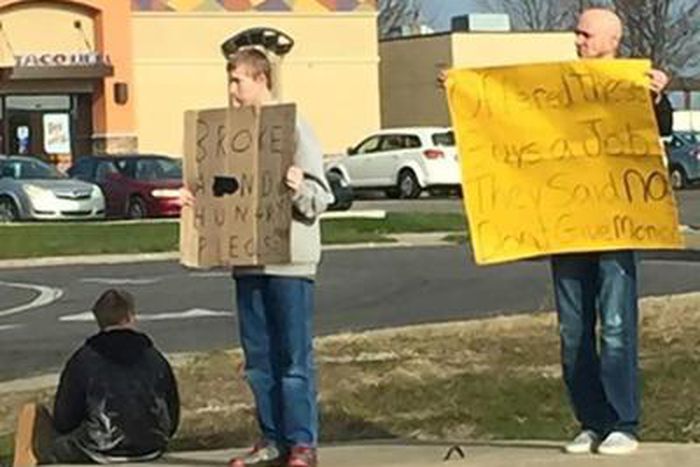 Mike Pothoff beside the panhandlers holding his sign