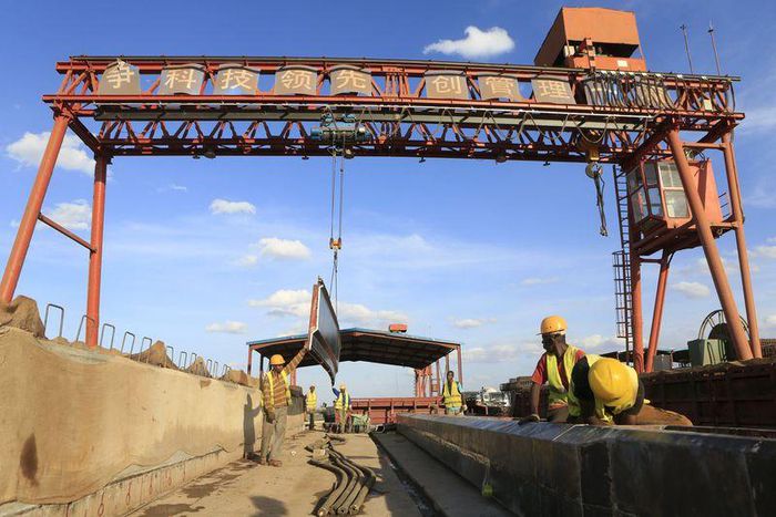 Workers are seen near a sign written in Chinese at the construction site of the Mombasa-Nairobi standard gauge railway (SGR) at Emali in Kenya October 10, 2015. Picture taken October 10, 2015. REUTERS/Noor Khamis