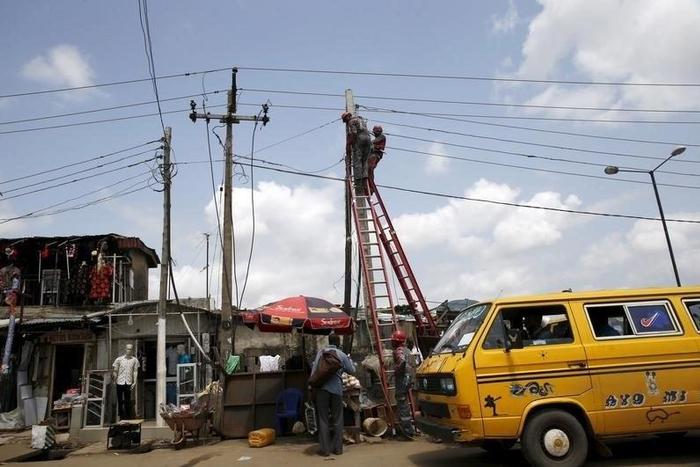 Power officials stand on ladders to fix electric cables along a road in Egbeda dstrict in Nigeria's commercial capital Lagos, July 1, 2015. Picture taken July 1, 2015. REUTERS/Akintunde Akinleye