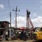 Power officials stand on ladders to fix electric cables along a road in Egbeda dstrict in Nigeria's commercial capital Lagos, July 1, 2015. Picture taken July 1, 2015. REUTERS/Akintunde Akinleye
