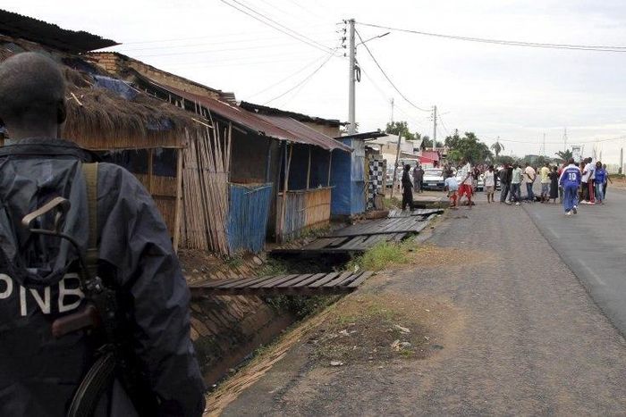A policeman watches as residents gather near the bodies of unidentified men killed during gunfire in the Nyakabiga neighborhood of Burundi's capital Bujumbura, December 12.