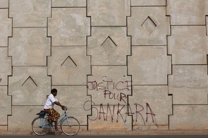 A woman rides a bicycle past graffiti reading "Justice for Sankara" in Ouagadougou, Burkina Faso, December 4, 2015. Picture taken December 4, 2015. REUTERS/Joe Penney