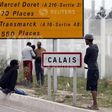 Migrants stand near a city sign along a road near the makeshift camp called "The New Jungle" in Calais, France, August 19, 2015. T REUTERS/Regis Duvignau