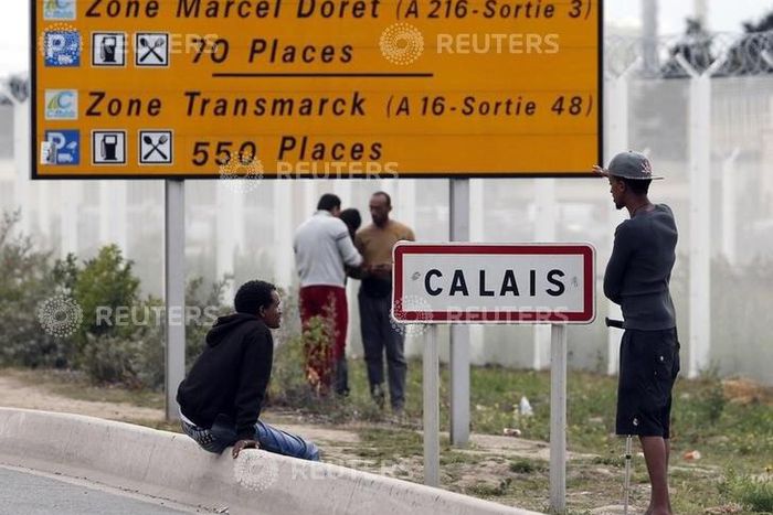 Migrants stand near a city sign along a road near the makeshift camp called "The New Jungle" in Calais, France, August 19, 2015. T REUTERS/Regis Duvignau