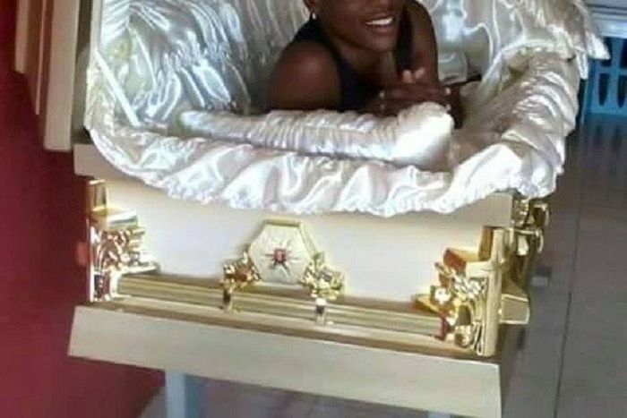 This lady is happy taking a selfie inside a coffin