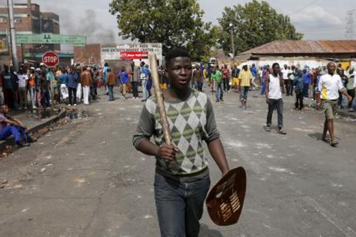A local gestures as he holds a stick and a shield outside a hostel during anti-immigrant related violence in Johannesburg, April 17, 2015.
