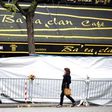 People look through the screened-off facade of the Bataclan Cafe adjoining the concert hall, one of the sites of the deadly attacks in Paris, November 21, 2015.
