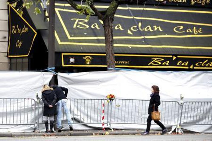 People look through the screened-off facade of the Bataclan Cafe adjoining the concert hall, one of the sites of the deadly attacks in Paris, November 21, 2015.