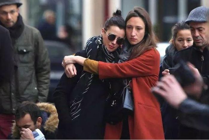 Women comfort each other as they stand in front of the Carillon cafe, in Paris, on Nov. 14, 2015.