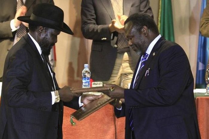 South Sudan's President Salva Kiir (L) and South Sudan's rebel commander Riek Machar exchange documents after signing a ceasefire agreement during the Inter Governmental Authority on Development (IGAD) Summit on the case of South Sudan in Ethiopia's ca...