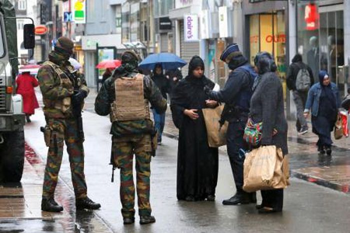 Belgian soldiers and a police officer control the documents of a woman in a shopping street in central Brussels, November 21, 2015, after security was tightened in Belgium following the fatal attacks in Paris.