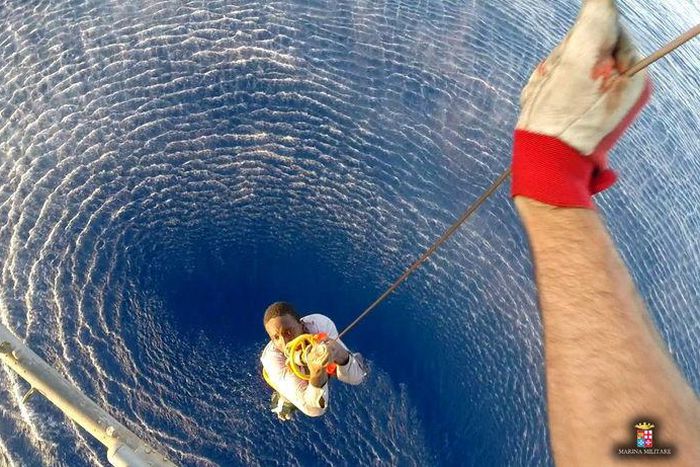 A migrant is rescued by an Italian Navy helicopter in the area where his boat sank in the Mediterranean Sea in this August 11, 2015 handout courtesy of the Italian Navy. REUTERS/Italian Navy/Handout via Reuters