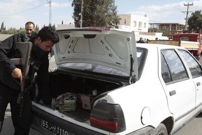 A police officer checks the back of a car at a checkpoint near the police headquarters in western Kasserine region October 23, 2014, as part of security measures ahead of the country's parliamentary elections on Sunday. REUTERS/Zoubeir Souissi
