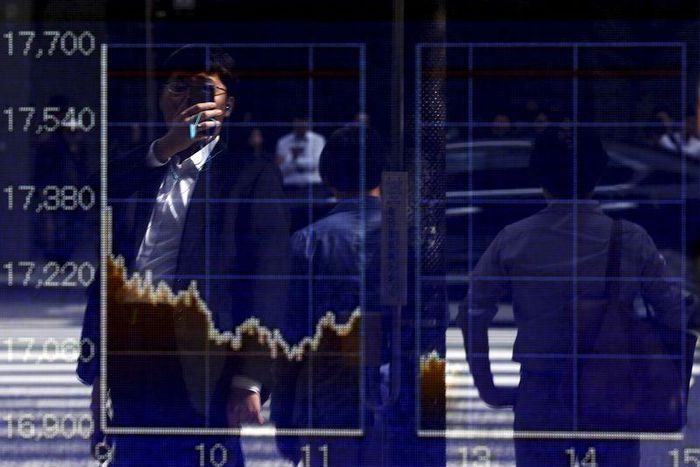 A man using a smartphone is reflected on a graph showing today's movements of Nikkei share average outside a brokerage in Tokyo, Japan, September 29, 2015.    REUTERS/Issei Kato